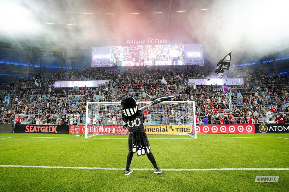 A mascot in front of a soccer crowd