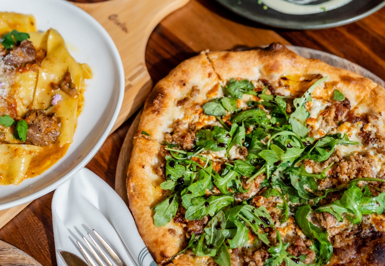 Pizza, pasta, and chicken on a wooden table