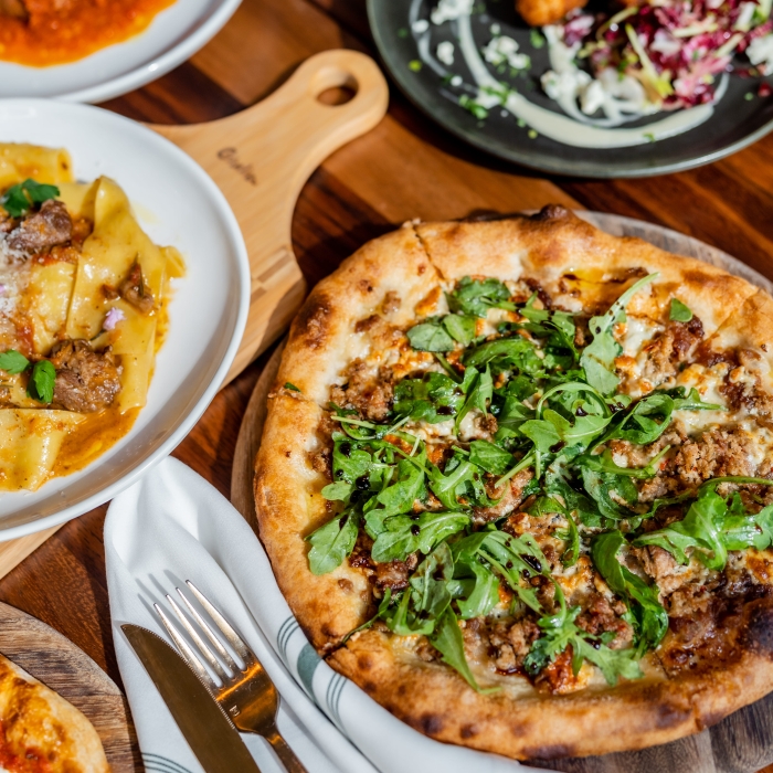 Pizza, pasta, and chicken on a wooden table