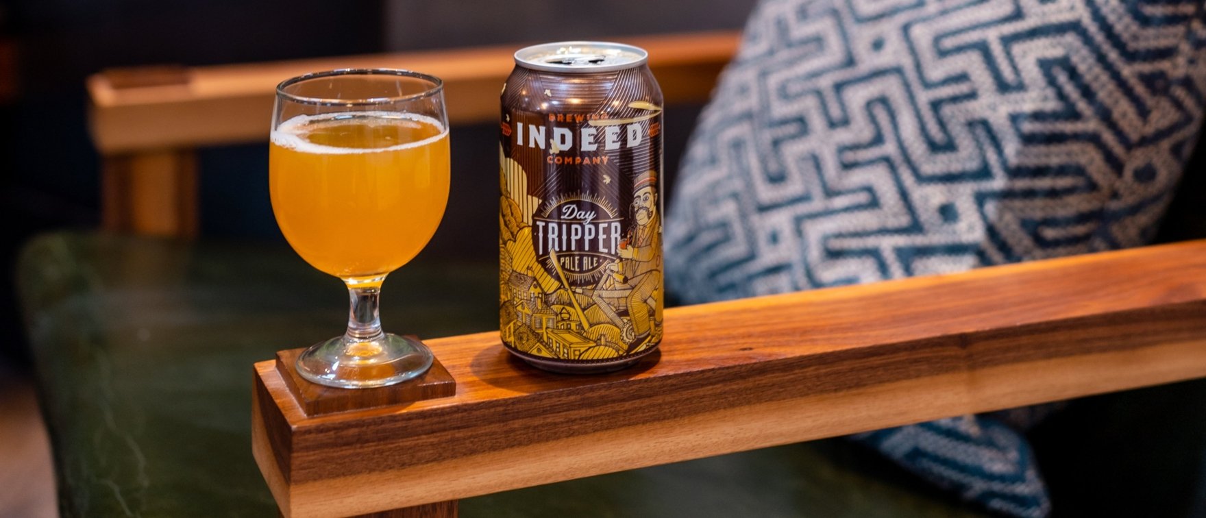 A glass of beer on the arm of a wooden chair