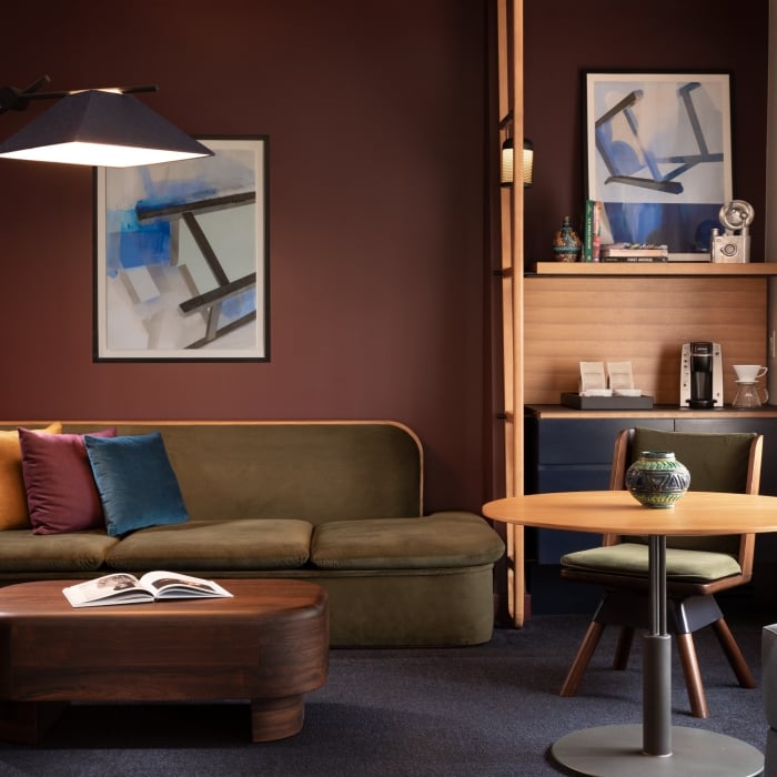 A green couch in a room with wooden furniture