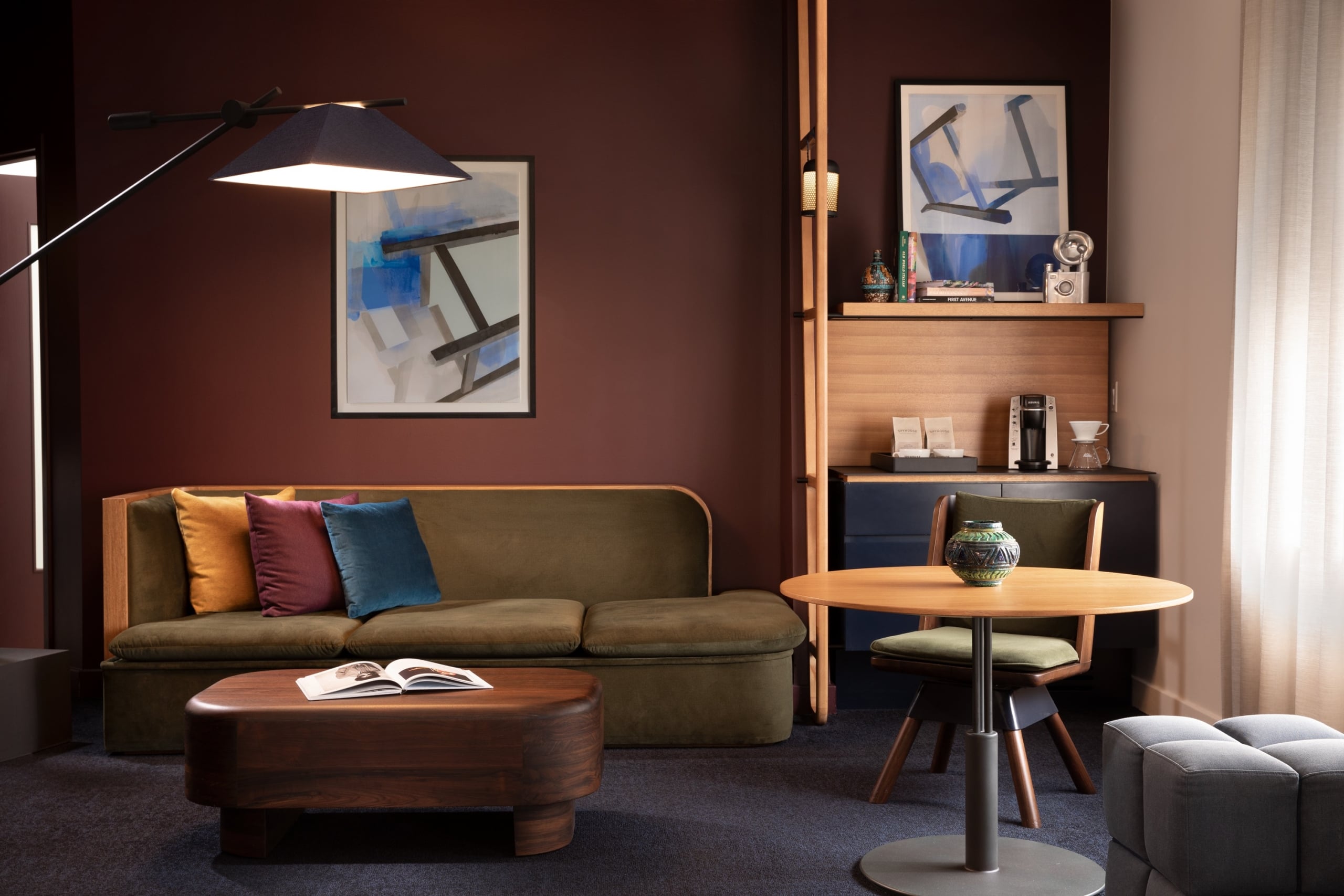 A green couch in a room with wooden furniture