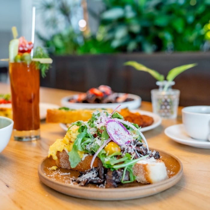Toast with toppings, bloody mary, parfait, and dishes in background on table