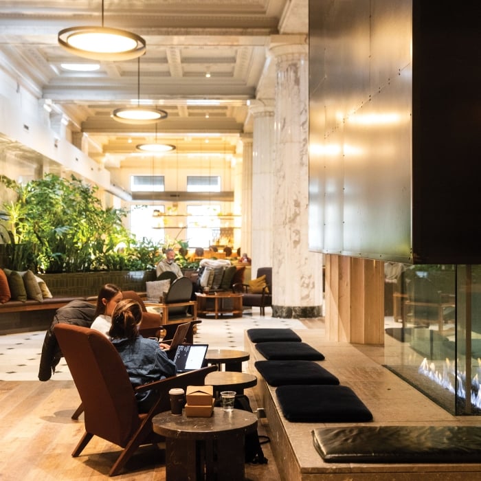 Lounge seating next to grand fireplace with plants in background