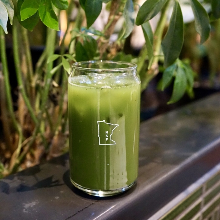 Glass of matcha drink on edge in plants