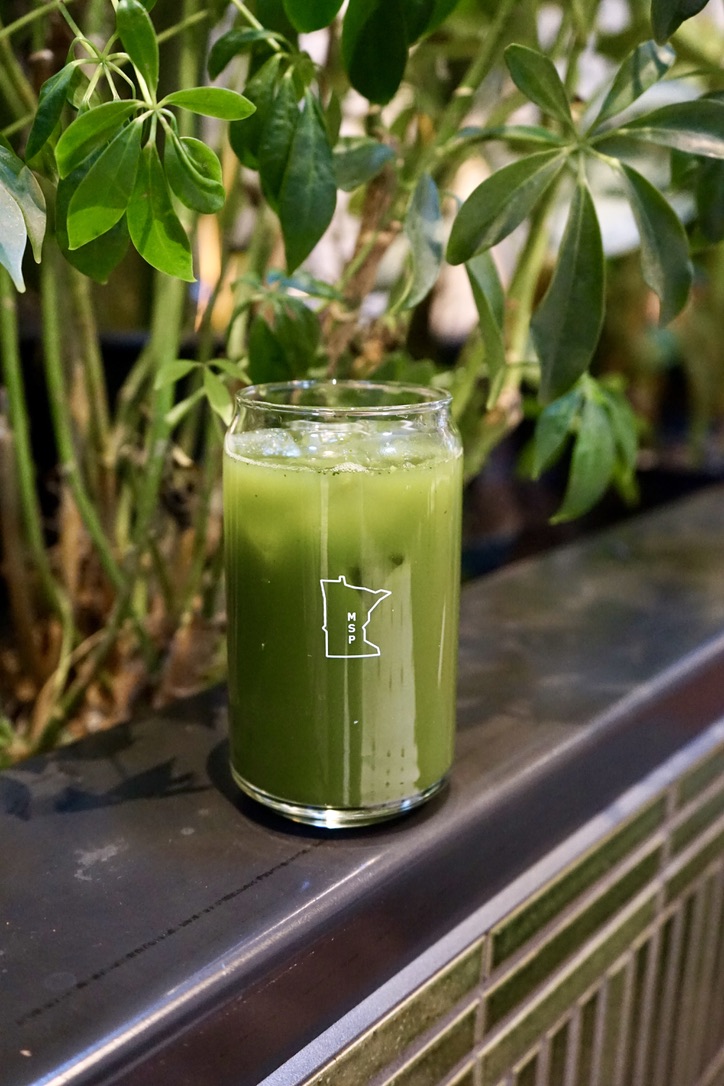 Glass of matcha drink on edge in plants