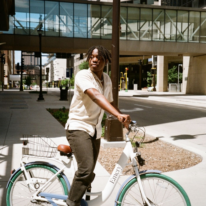 Man standing on bike with Emery branding with Minneapolis city street in background