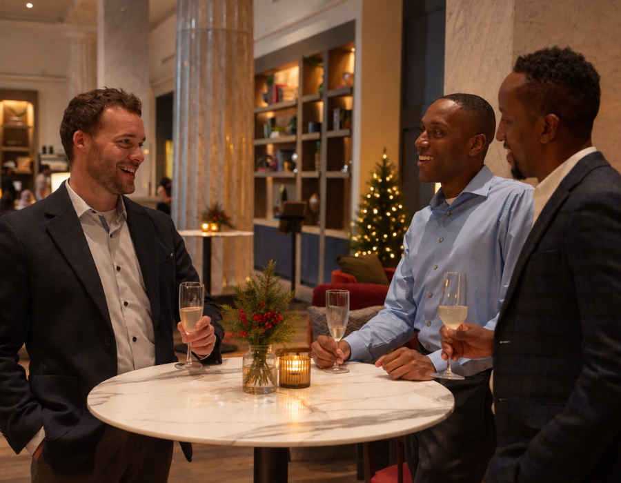 Three men laughing with glasses of champagne in elegant holiday setting